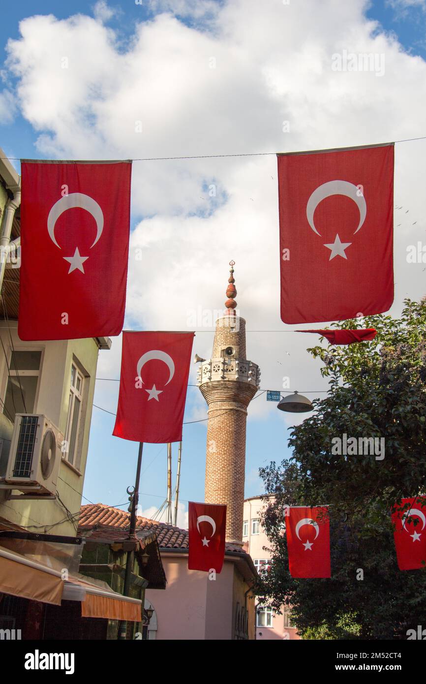 Turkish national flag hang on a pole on a rope with a minaret