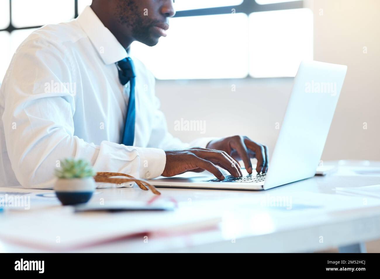 Back to work. an unrecognizable businessman typing on his laptop while being seated at a desk in the office during the day. Stock Photo