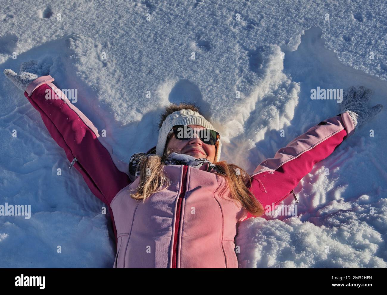 Portrait of mature woman having fun lying in snow, Austria Stock Photo