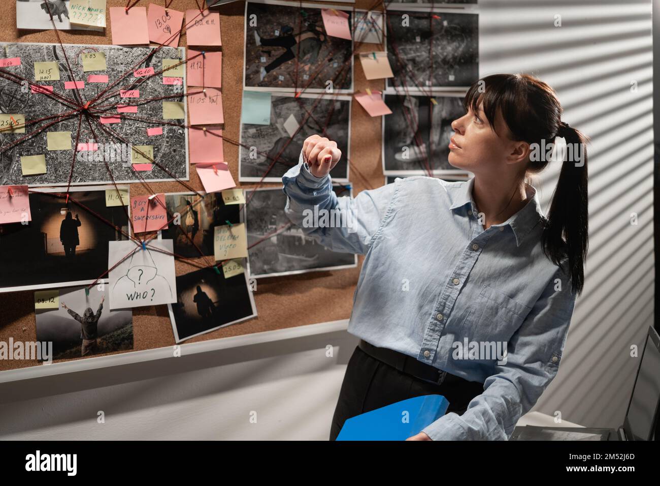 Detective looking at evidence board in her office, analyzing case