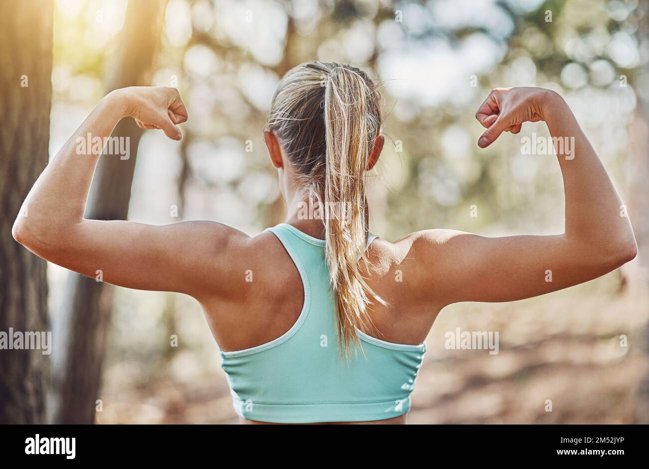Young fitness woman flexing big strong biceps muscles towards the sun at  urban beach. Cheerful female bodybuilder showing arms. Workout success  concept. Photos