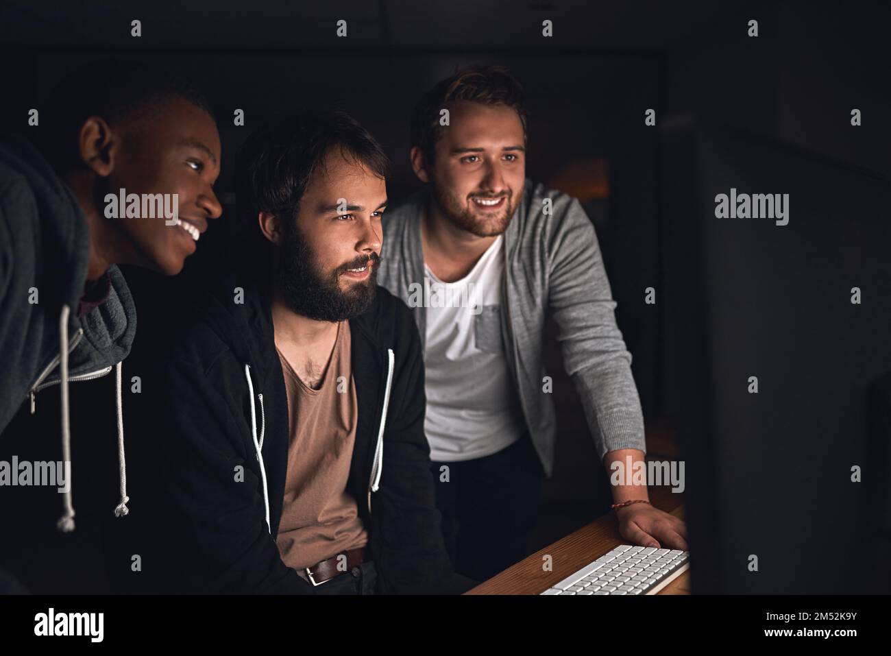 Working together on new code. young computer programmers working late in the office. Stock Photo