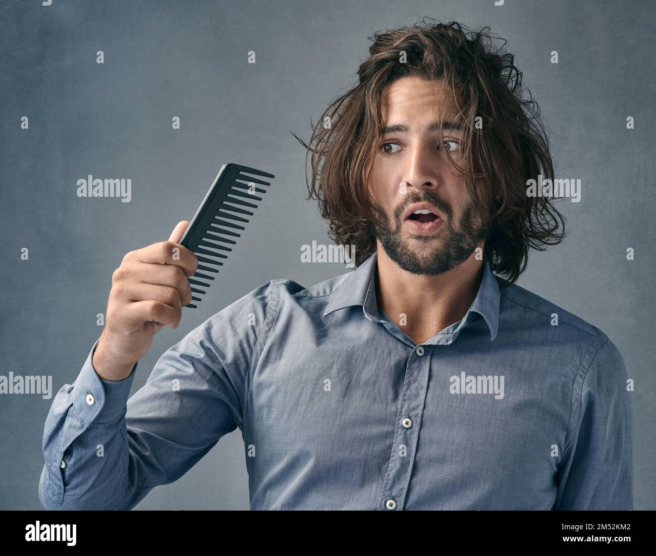 Arent you suppose to fix the mess on my head. a handsome young man looking at the comb after combing his hair. Stock Photo