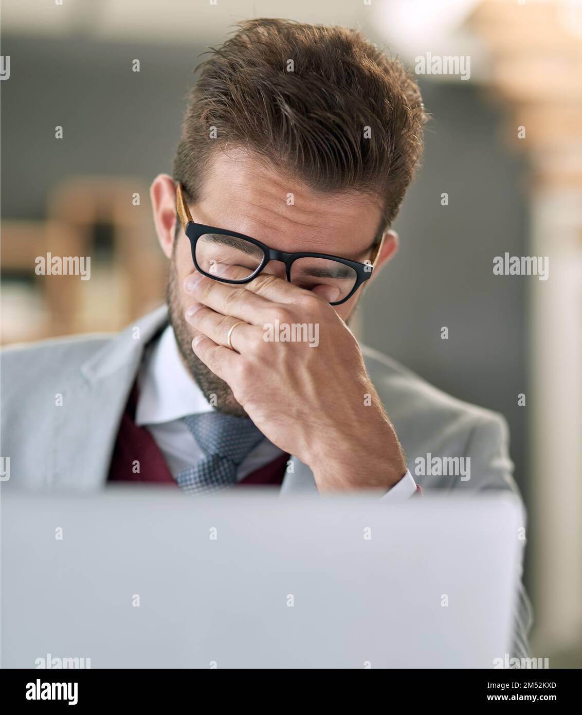 Cant deal. a businessman feeling exhausted while using a laptop at his office desk. Stock Photo