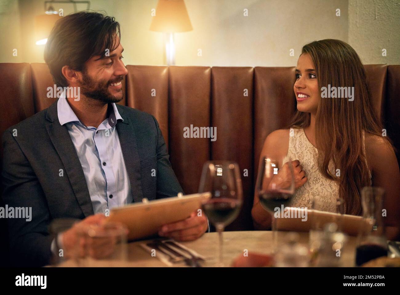 Romance is on the menu. a happy young couple reading the menu during a romantic dinner date at a restaurant. Stock Photo