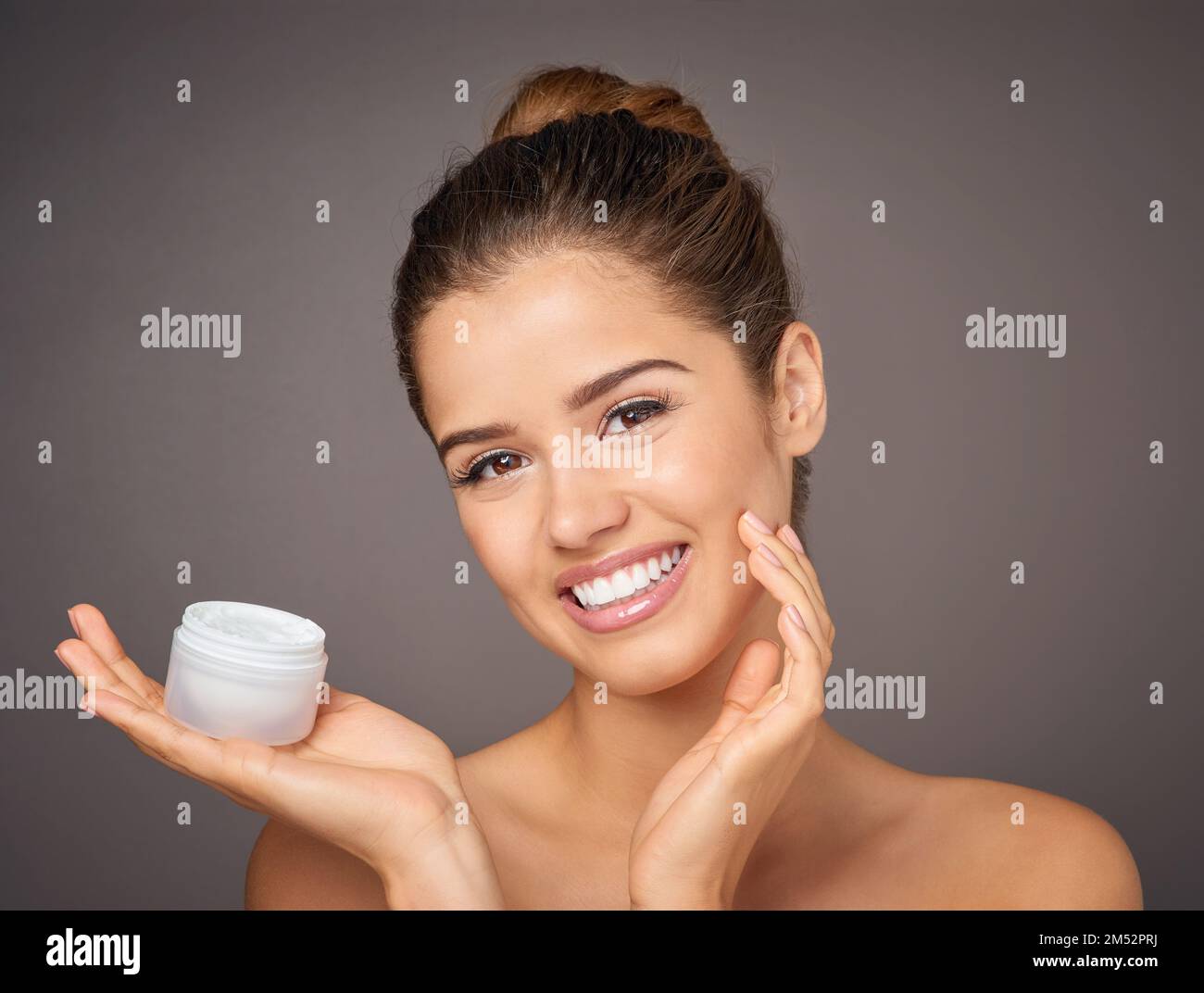 Youll feel the difference. Portrait of a beautiful young model holding up a tub of skin cream in studio. Stock Photo