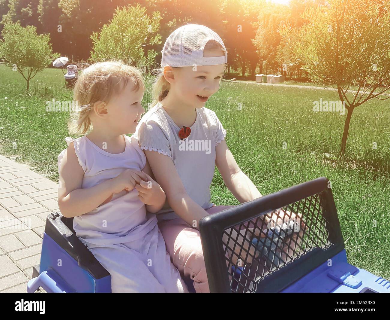 two little sisters sitting in a toy car Stock Photo - Alamy