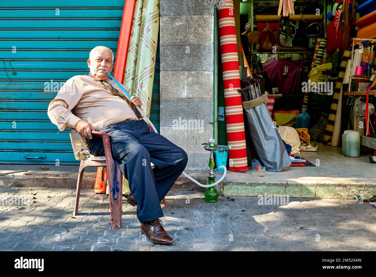 Amman Jordan. A relaxed senior citizen smoking shisha by his shop Stock Photo