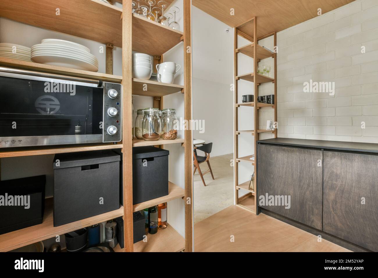 a kitchen with wooden shelves and black appliances on the shelfs in front of the oven, microwave and toaster Stock Photo