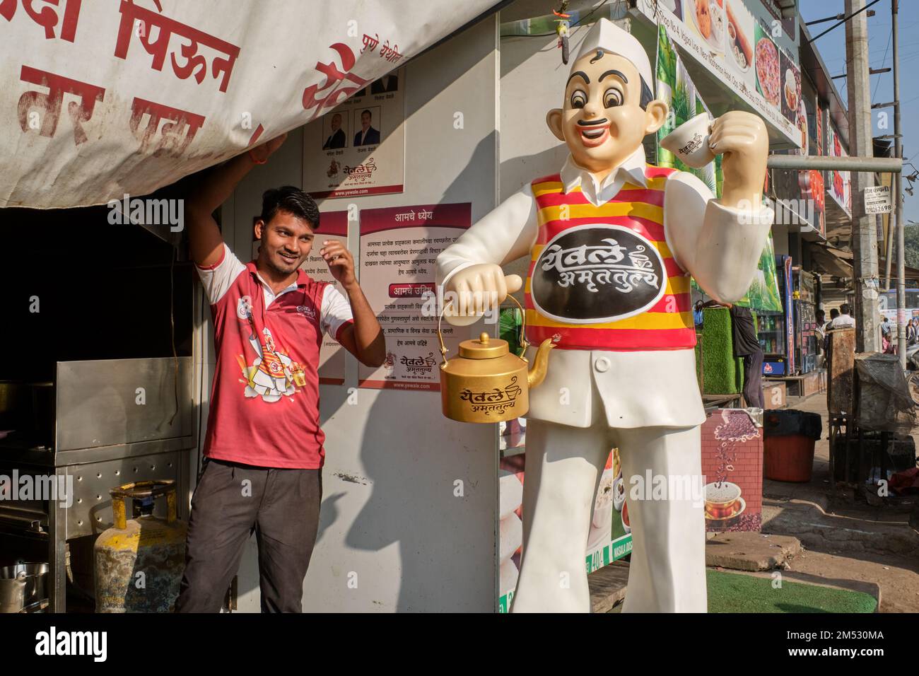 An employee of teashop chain Yevale Amruttulya, posing next to the company's trademark tea boy statue; in Kurla, Mumbai, India Stock Photo