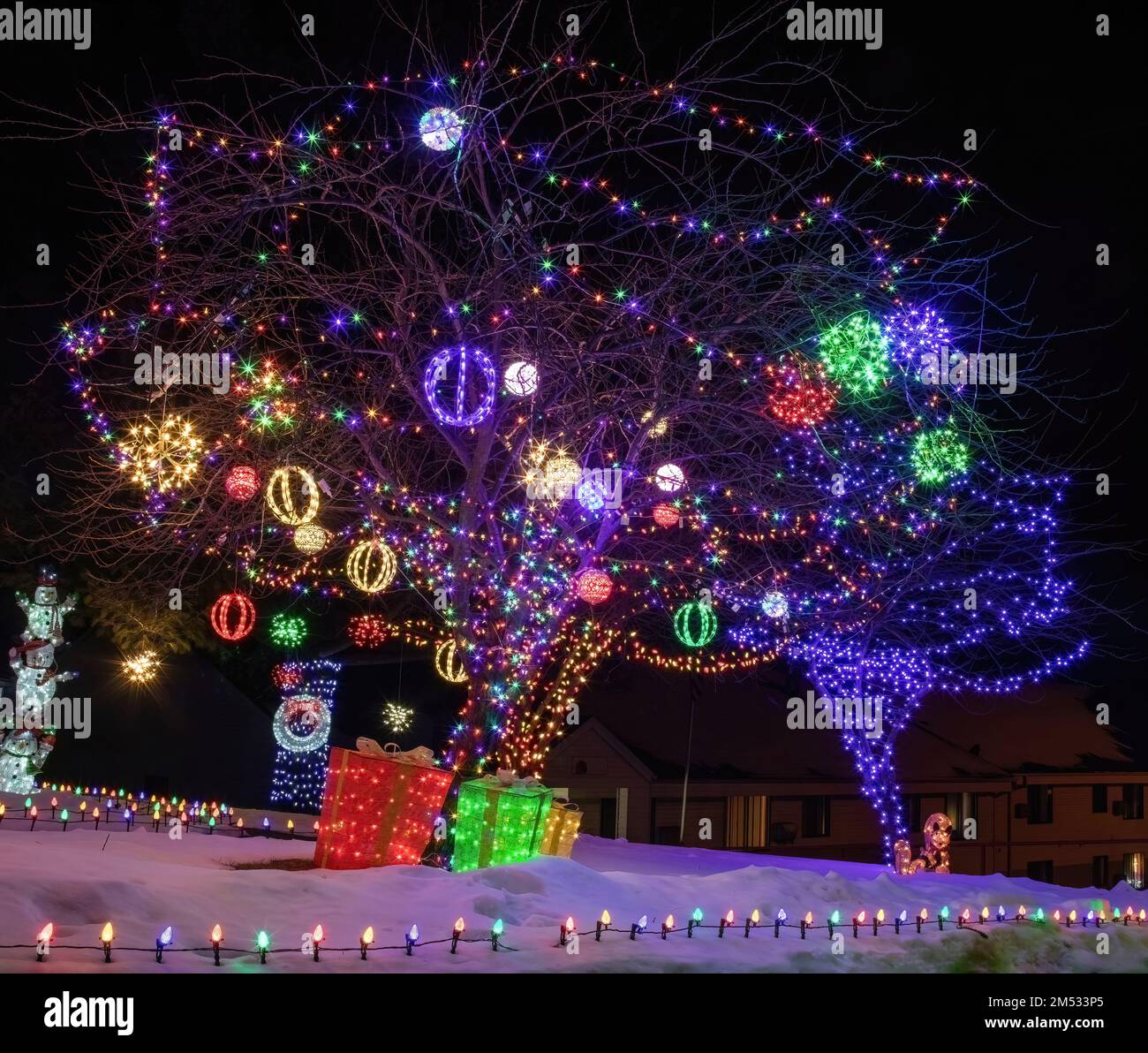 Lighted tree with ornaments and gifts under the tree for Christmas on a winter evening in St. Croix Falls, Wisconsin USA. Stock Photo