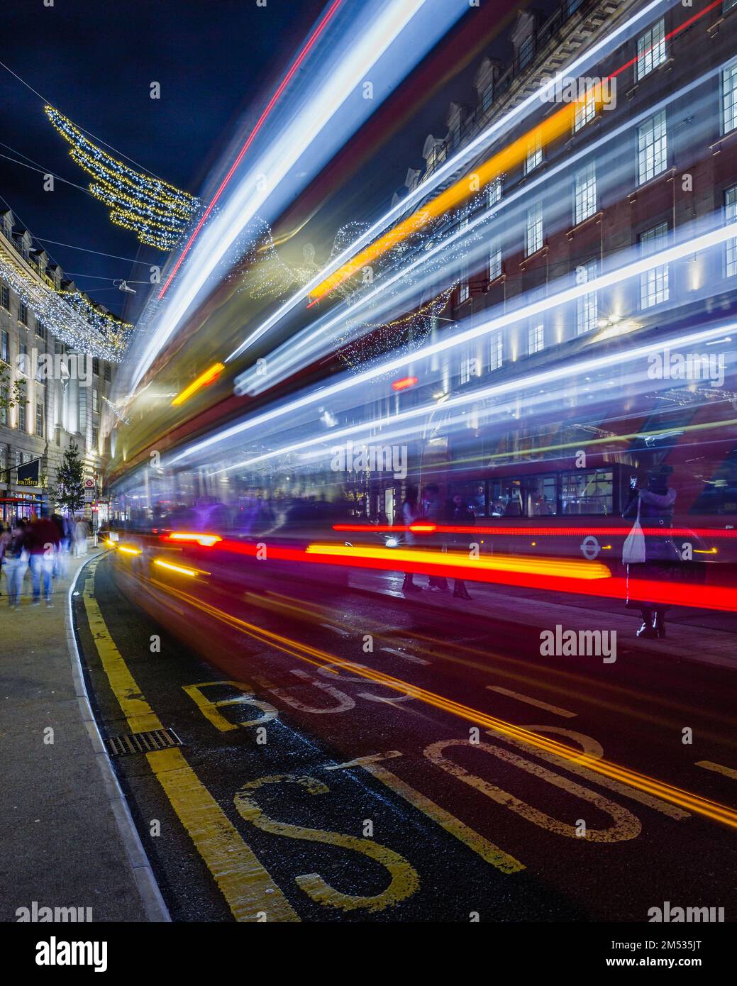 Light trails of a bus pass by a bus stop on London's Regent Street. Stock Photo