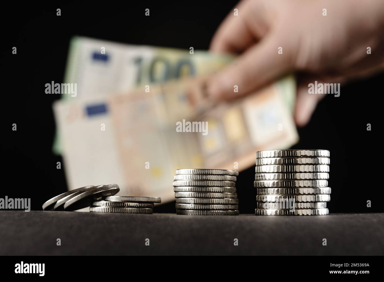 Coins and money on a dark background. Hand holding money for loans for planned investments in a future concept. Stock Photo