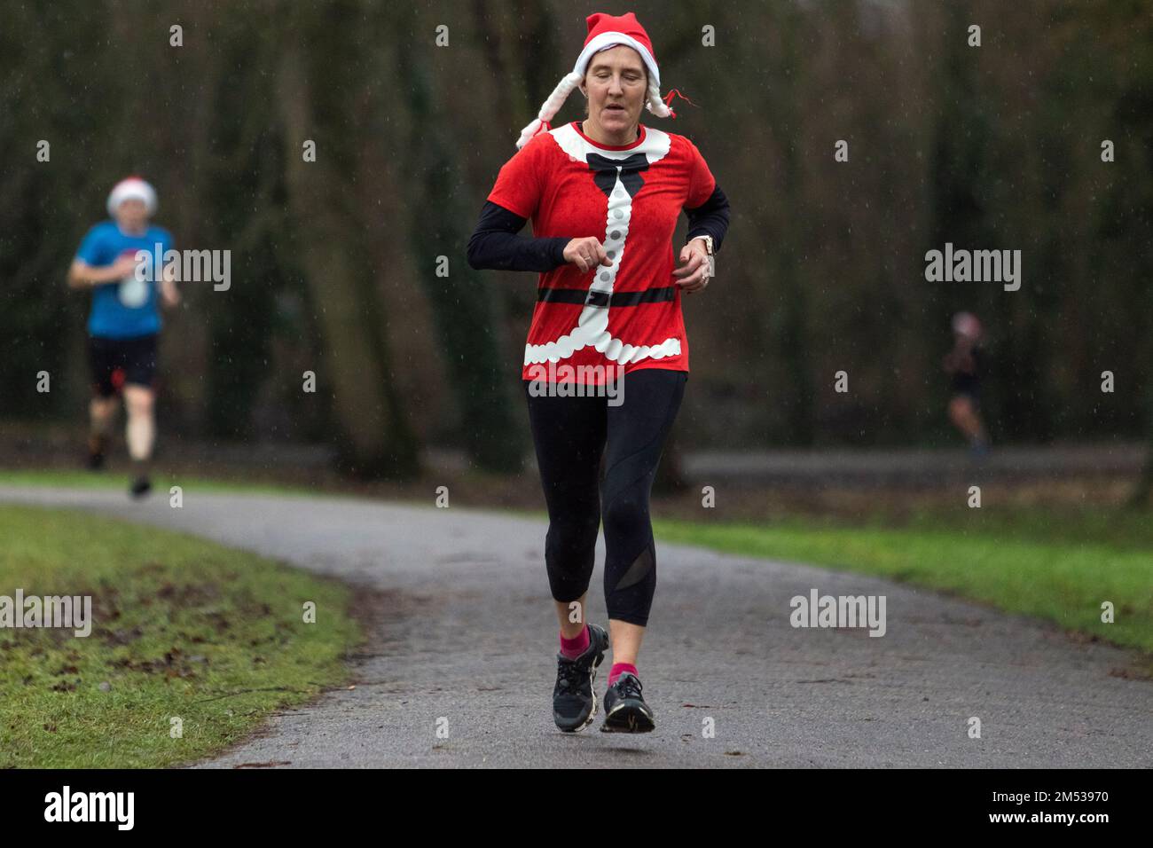 Chippenham, Wiltshire, UK. 25th December, 2022. A runner in fancy dress is pictured as she takes part in an early morning Christmas day 5km parkrun in Monkton Park, Chippenham, Wiltshire. The wet weather did nothing to dampen the spirits of the 200-300 people who participated in the event with many of them dressing up in fancy dress. Credit: Lynchpics/Alamy Live News Stock Photo
