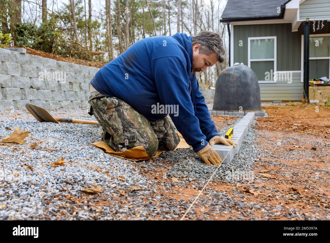 Using professional paver worker master lays down stones for pathway paving project. Stock Photo