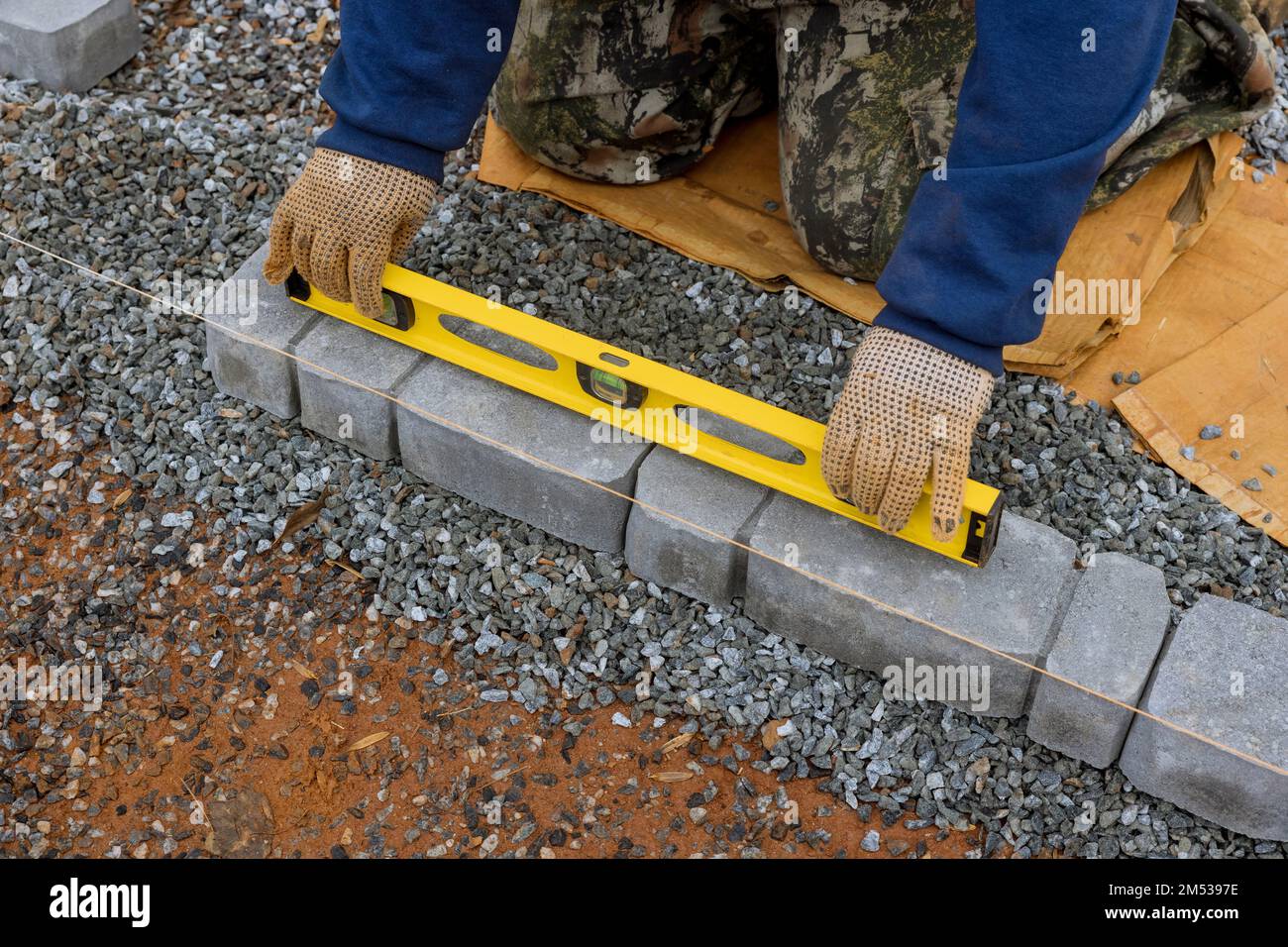 In process of laying stones pathway paving, professional paver worker is performing work. Stock Photo