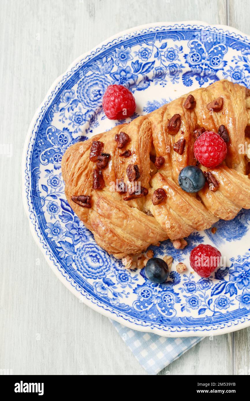 Braided danish bun made of puff pastry decorated with fresh fruits. Tasty breakfast. Stock Photo