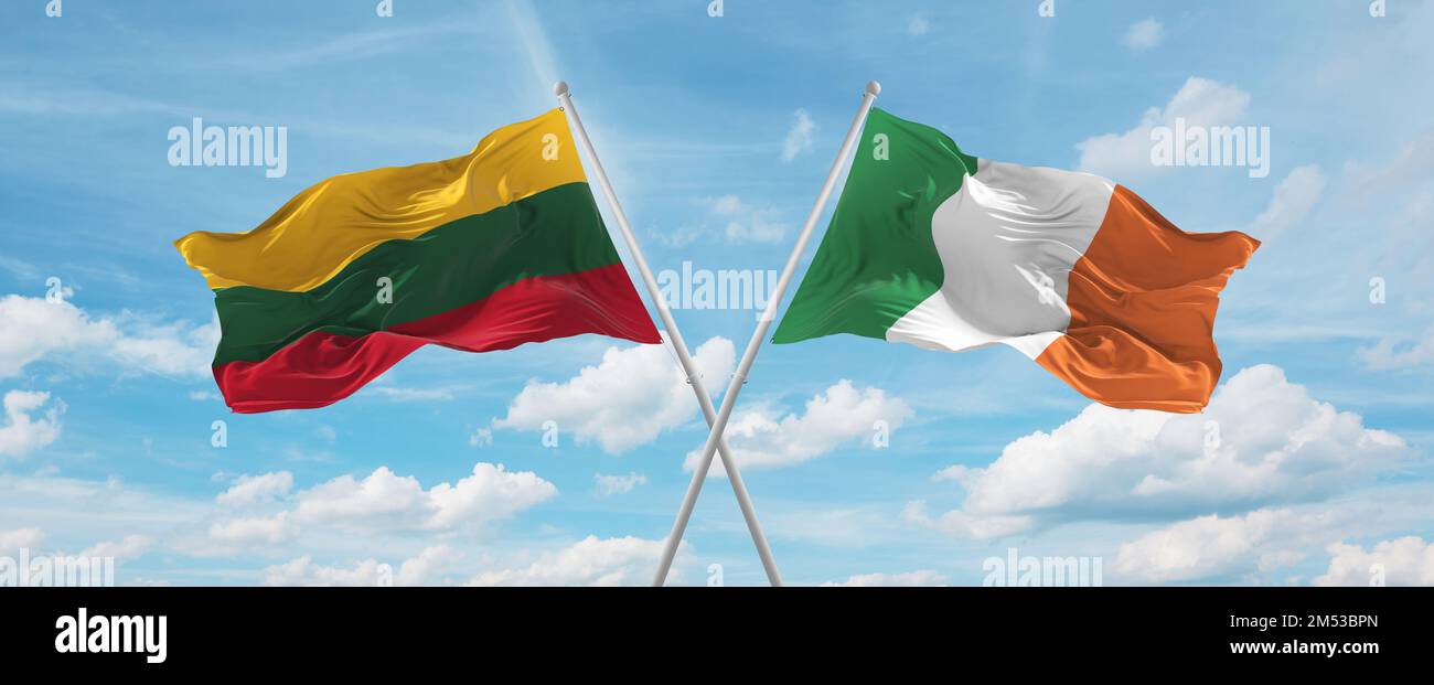 two crossed flags Ireland and Lithuania waving in wind at cloudy sky ...
