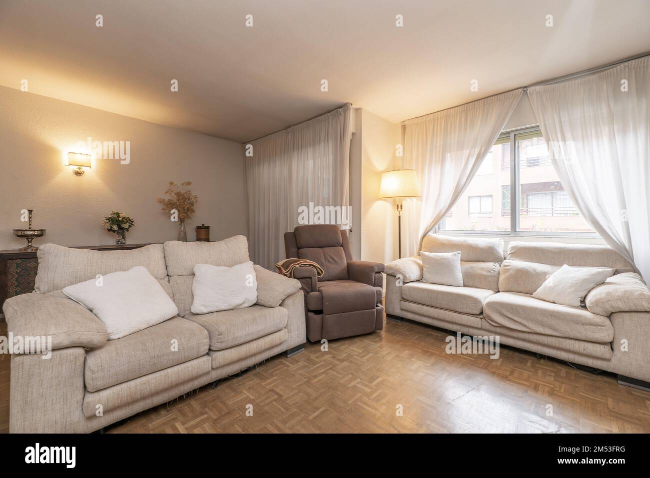Corner of a living room with twin armchairs upholstered in beige fabric and a massage chair in the middle Stock Photo