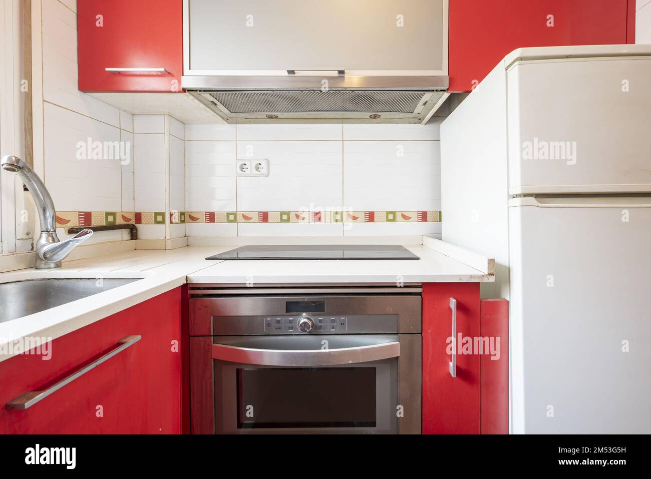 Used kitchen with red and white cabinets, matching stainless steel oven with sink Stock Photo