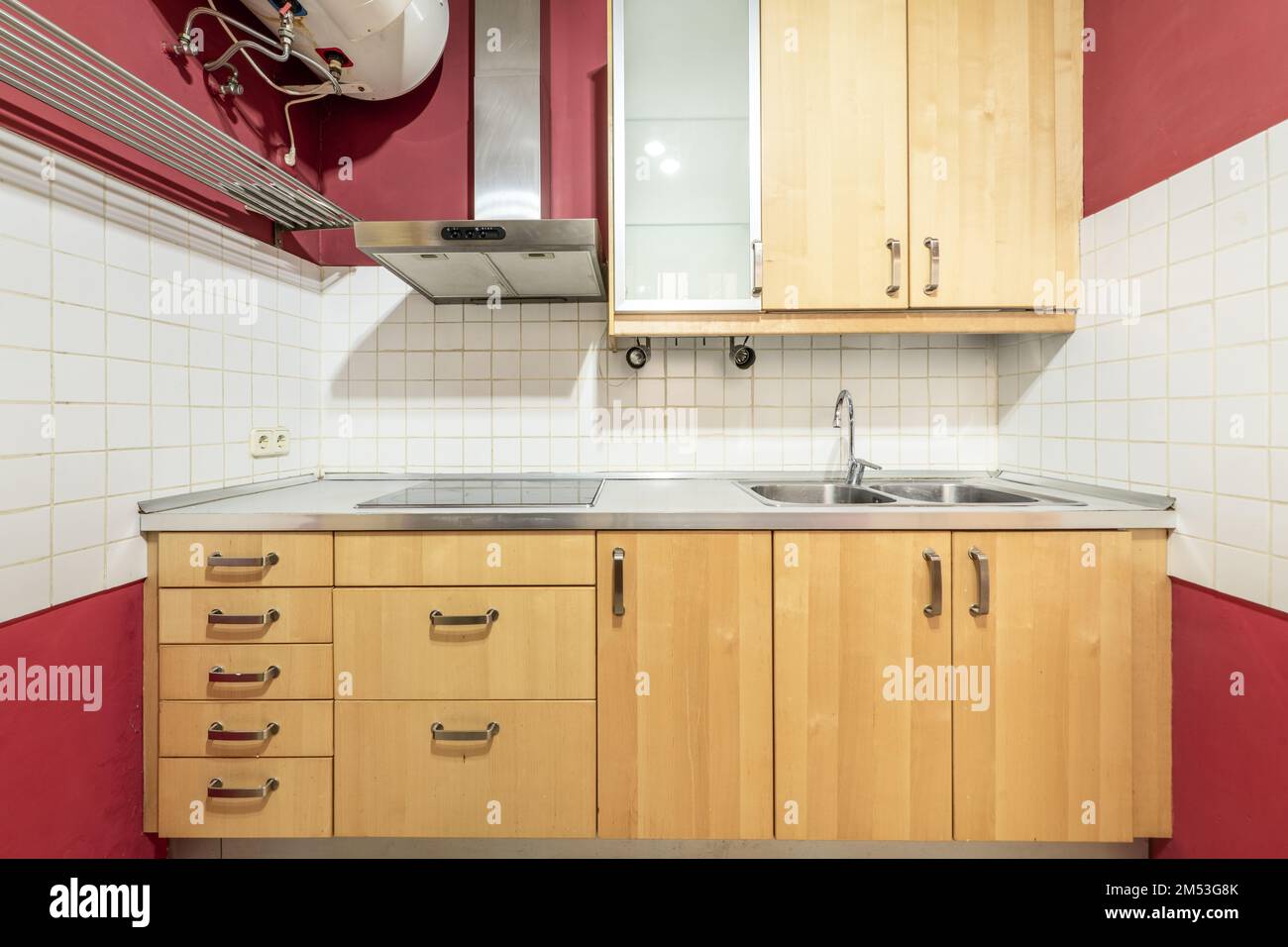 Front of a kitchen with wooden furniture with stainless steel countertop and ceramic hob with
