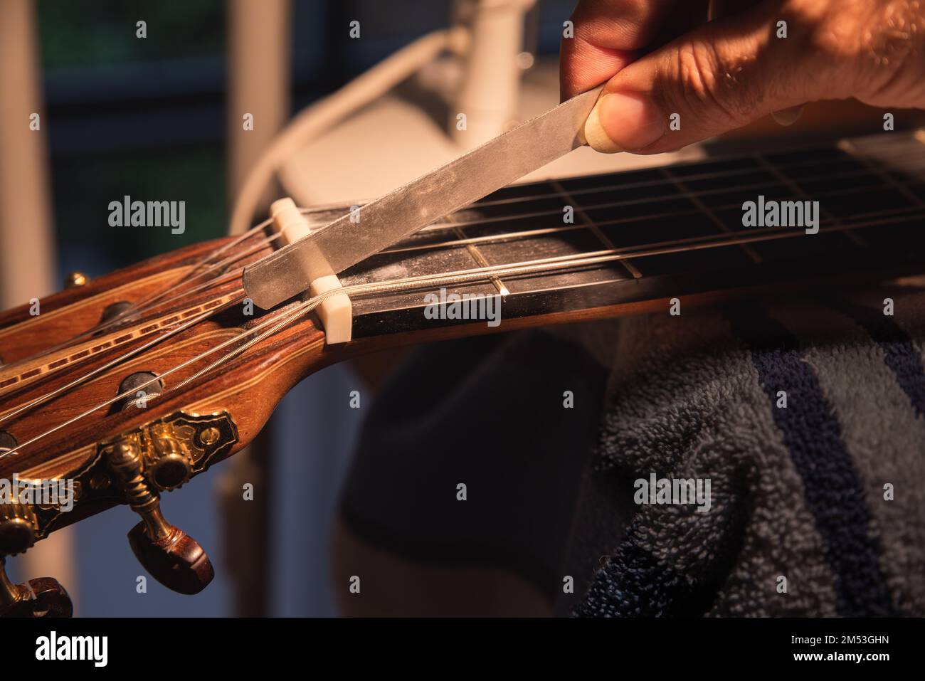 Musical instrument guitar repair and service worker hand uses file to