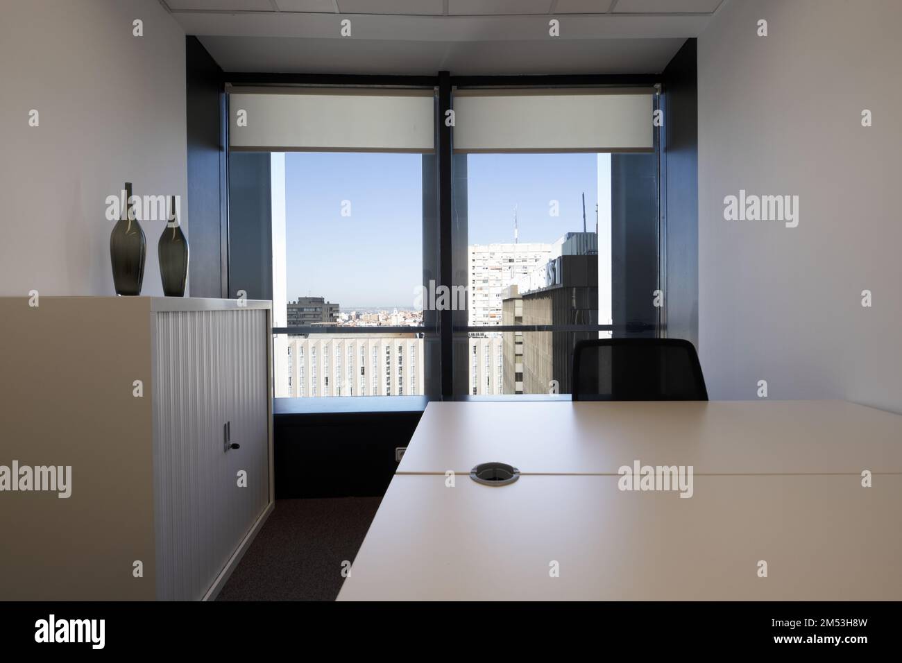 Coworking office with lockable filing cabinet, decorative glass vases and bay window with views Stock Photo