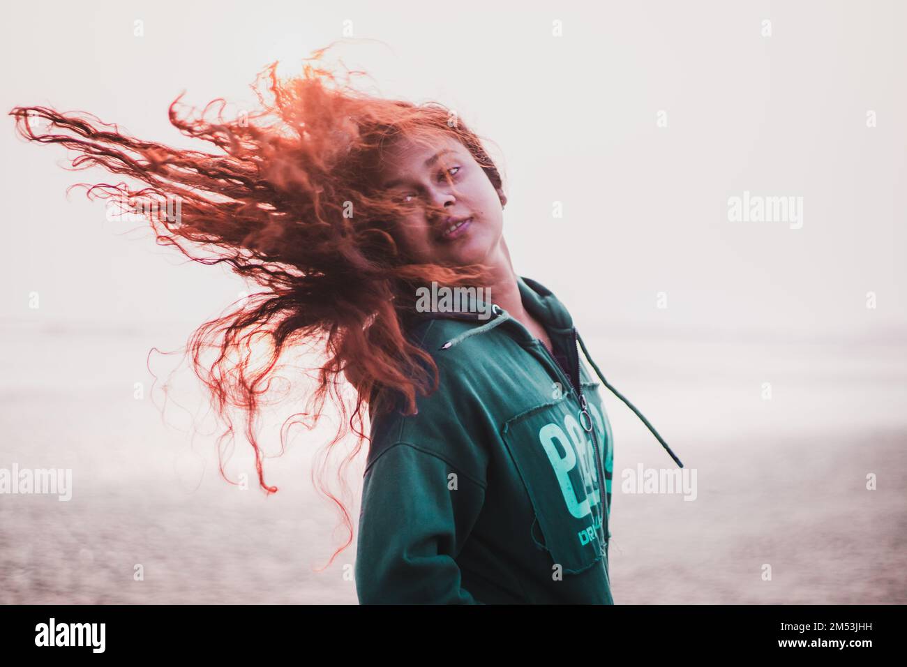 The portrait of an Indian girl playing with her orange hair Stock Photo