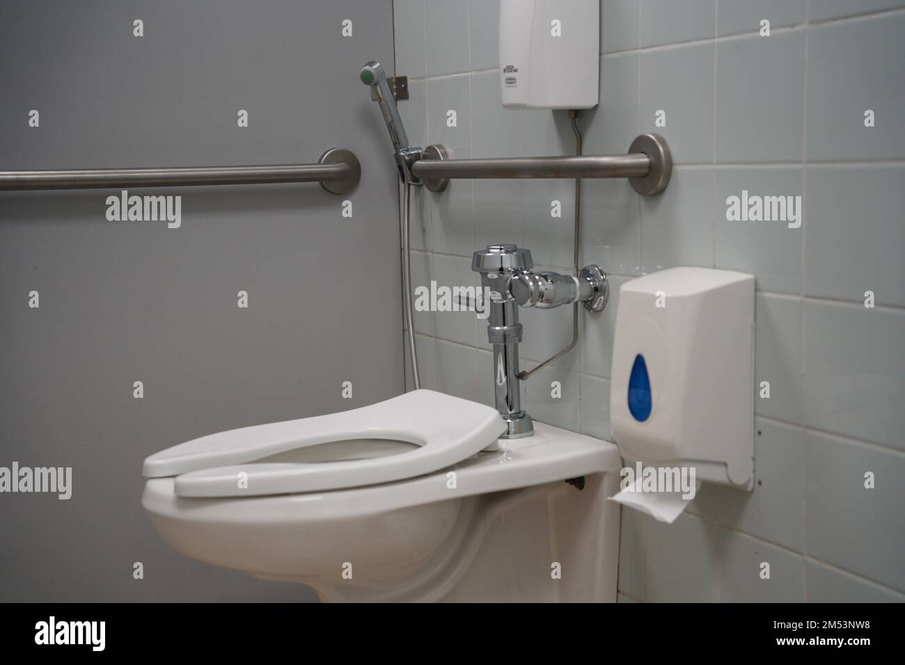 School, university or public handicap toilet, white toilet with washing tool or 'shattaf' and trash can. Arabian toilet with washing spray, modern toi Stock Photo