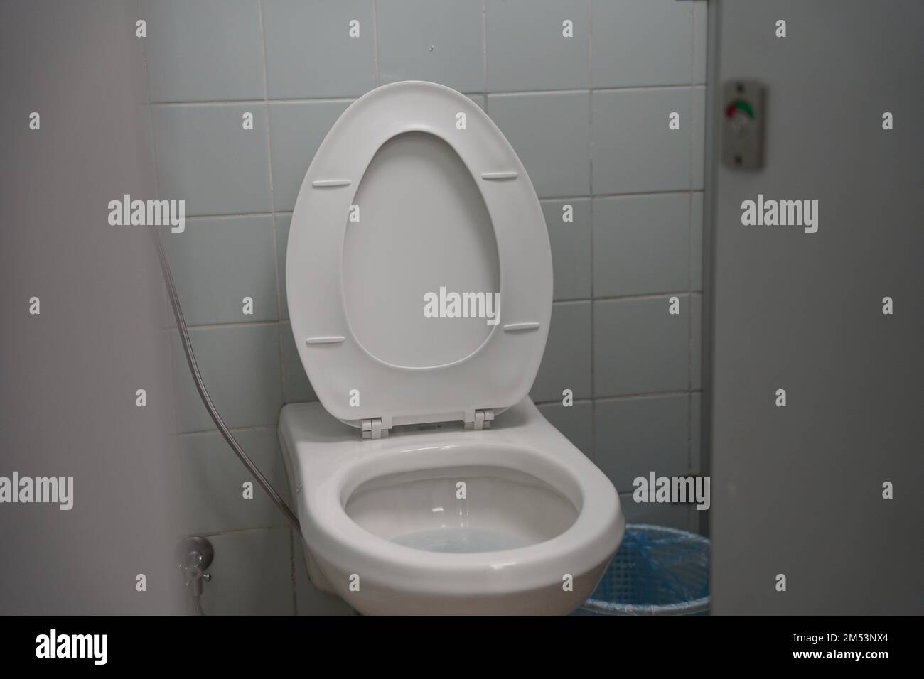 School, university or public toilet, white toilet with washing tool or 'shattaf' and trash can. Arabian toilet with the washing spray, modern toilet. Stock Photo