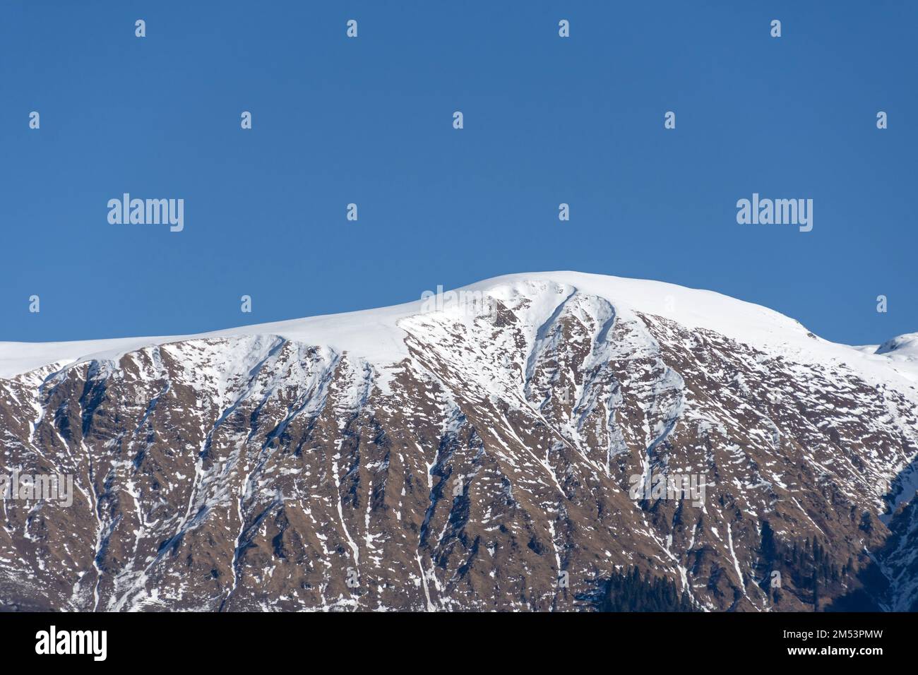 Snow-capped mountain peaks illuminated by the sun in winter Stock Photo