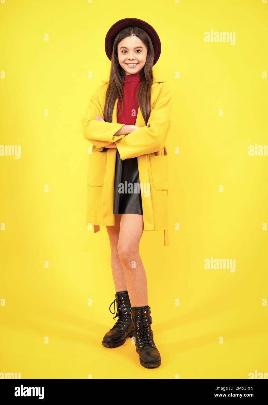 Full length of pretty cheerful teenager girl having fun good mood and posing in casual autumn coat isolated over yellow background. Happy teenager Stock Photo