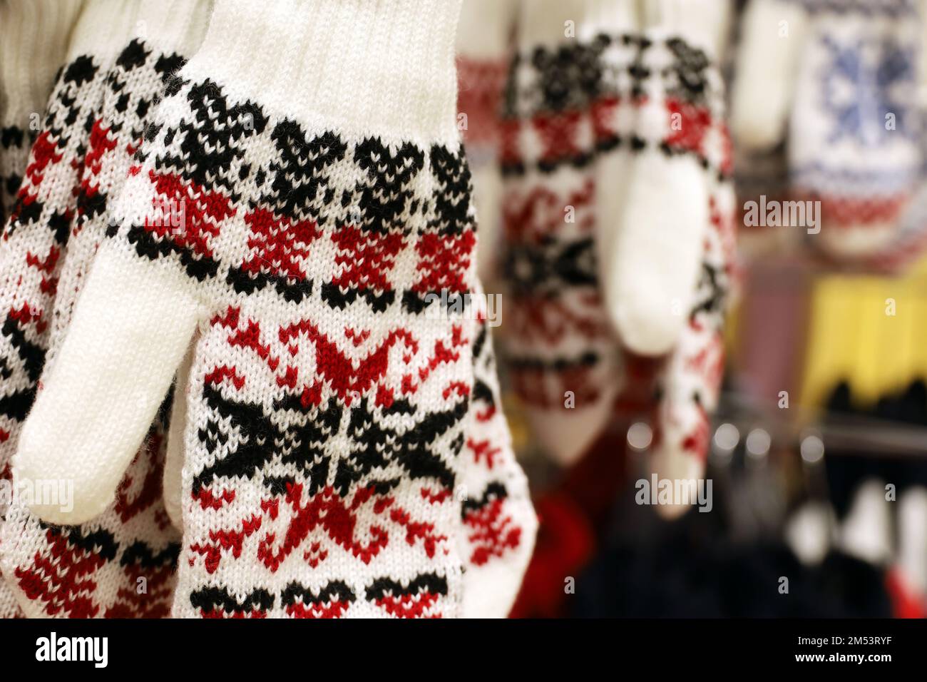 Knitted gloves with New Year pattern hanging in a store. Warm clothing for winter holidays Stock Photo