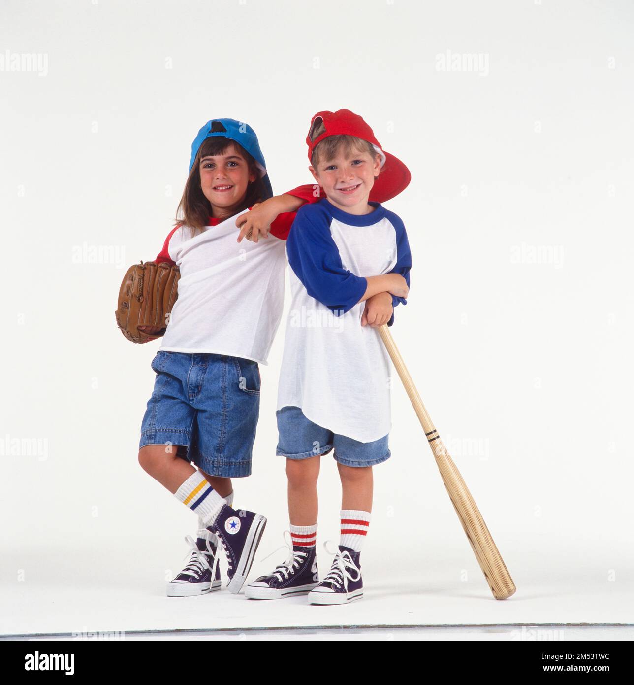 A little boy and girl dressed in baseball outfit with sneakers and hats