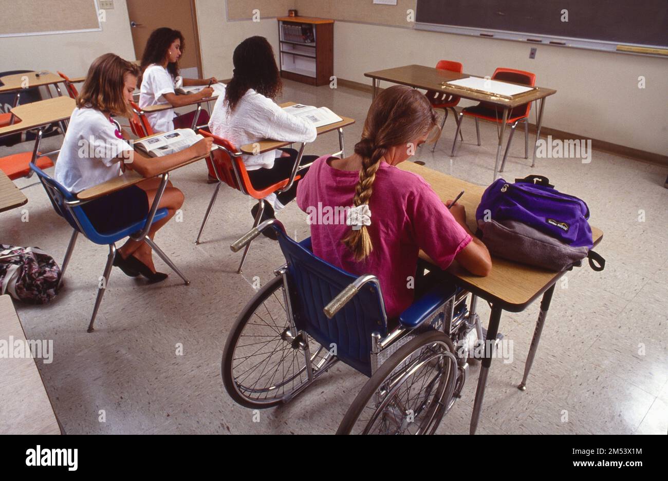 Teenage girls sitting at their desks in the classroom doing school work ...