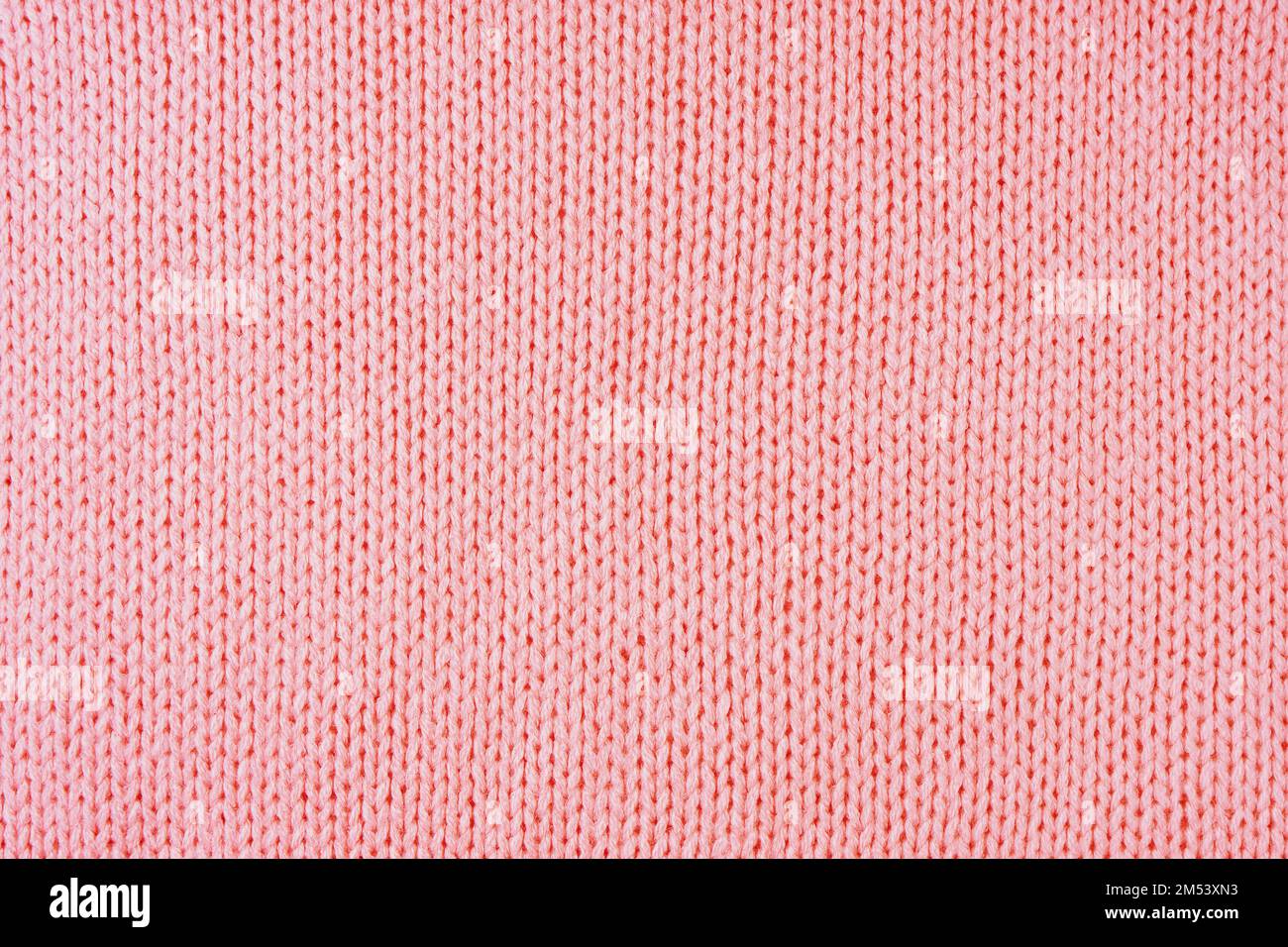 Close up background of knitted wool fabric made of viscose yarn. Pastel red color wool knitwear texture. Abstract knitted jersey background. Fabric ab Stock Photo