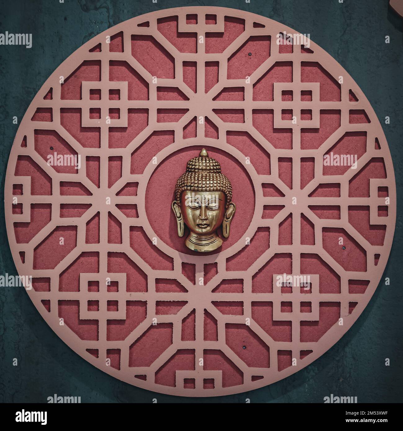 A buddha head in a circular pattern on a wall Stock Photo