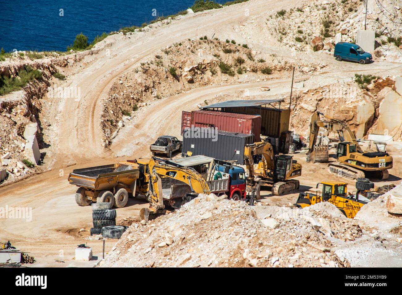 An open-pit mine of white marble stone with heavy machinery used to extract and mine the precious stone for further use and production Stock Photo