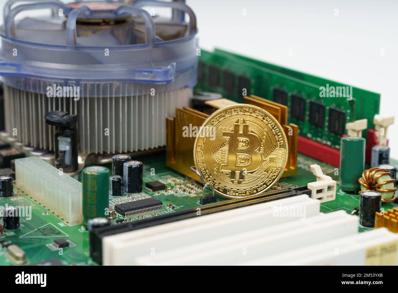Business and technology concept. There is a golden bitcoin coin on the motherboard of the computer. Stock Photo