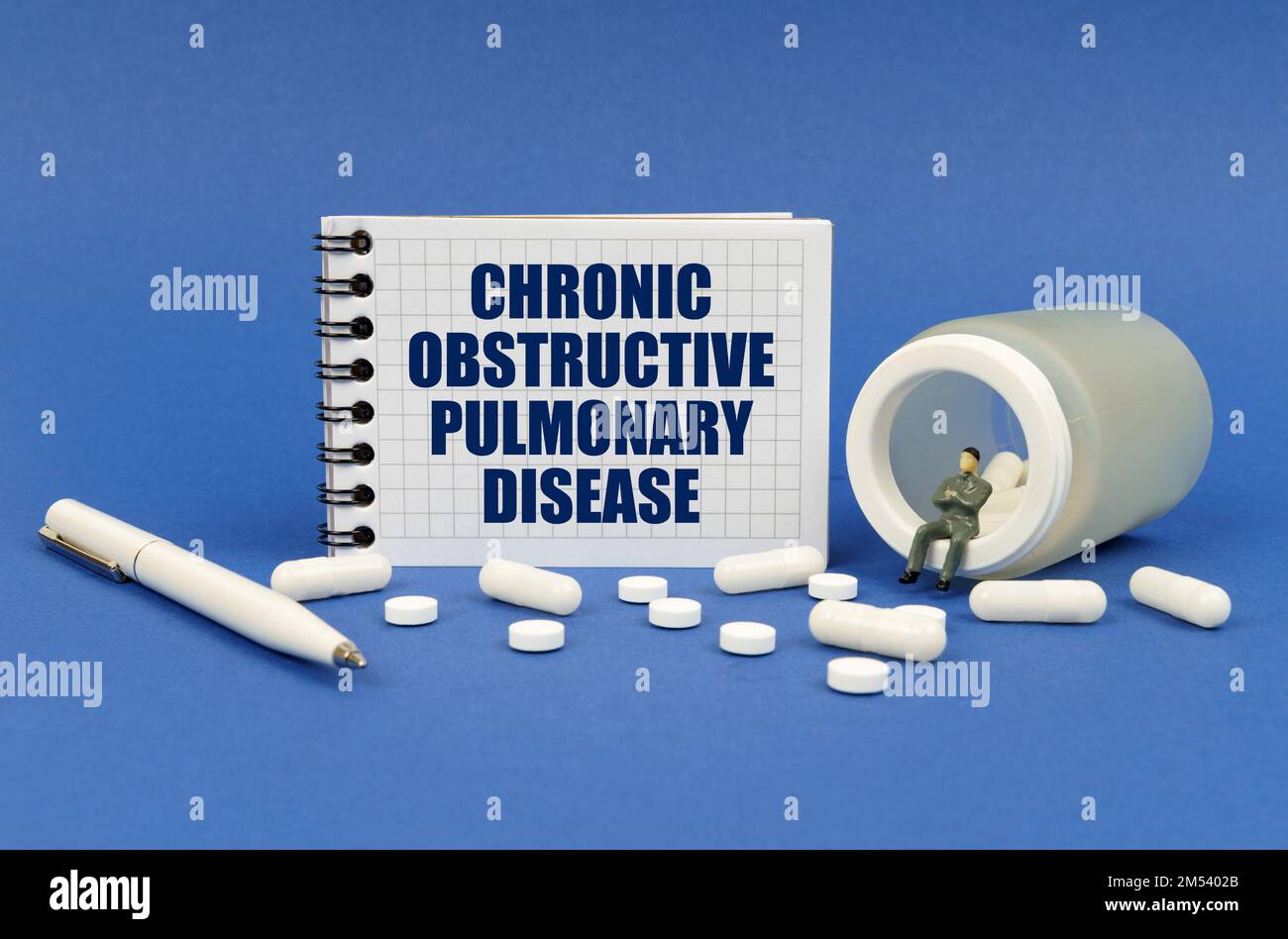 Medical concept. On a blue surface there is a jar of pills, a figure of a man, a notepad with the inscription - Chronic obstructive pulmonary disease Stock Photo