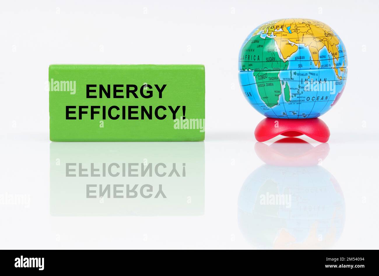 Ecological concept. On a reflective surface is a globe and a green sign with the inscription - Energy Efficiency Stock Photo