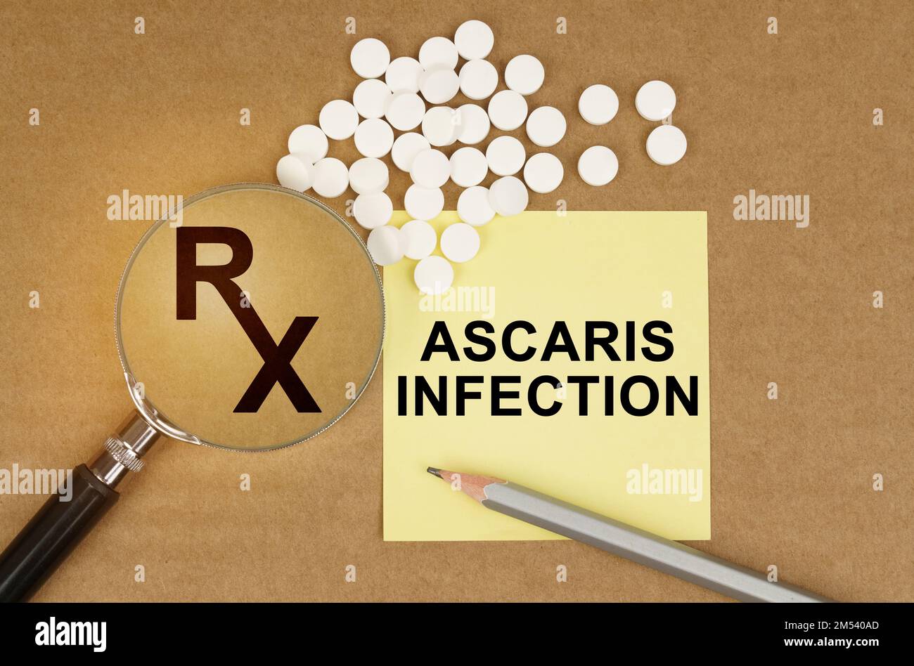 Medical concept. On the table are pills, a magnifying glass, pencils and a sticker with the inscription - Ascaris Infection Stock Photo