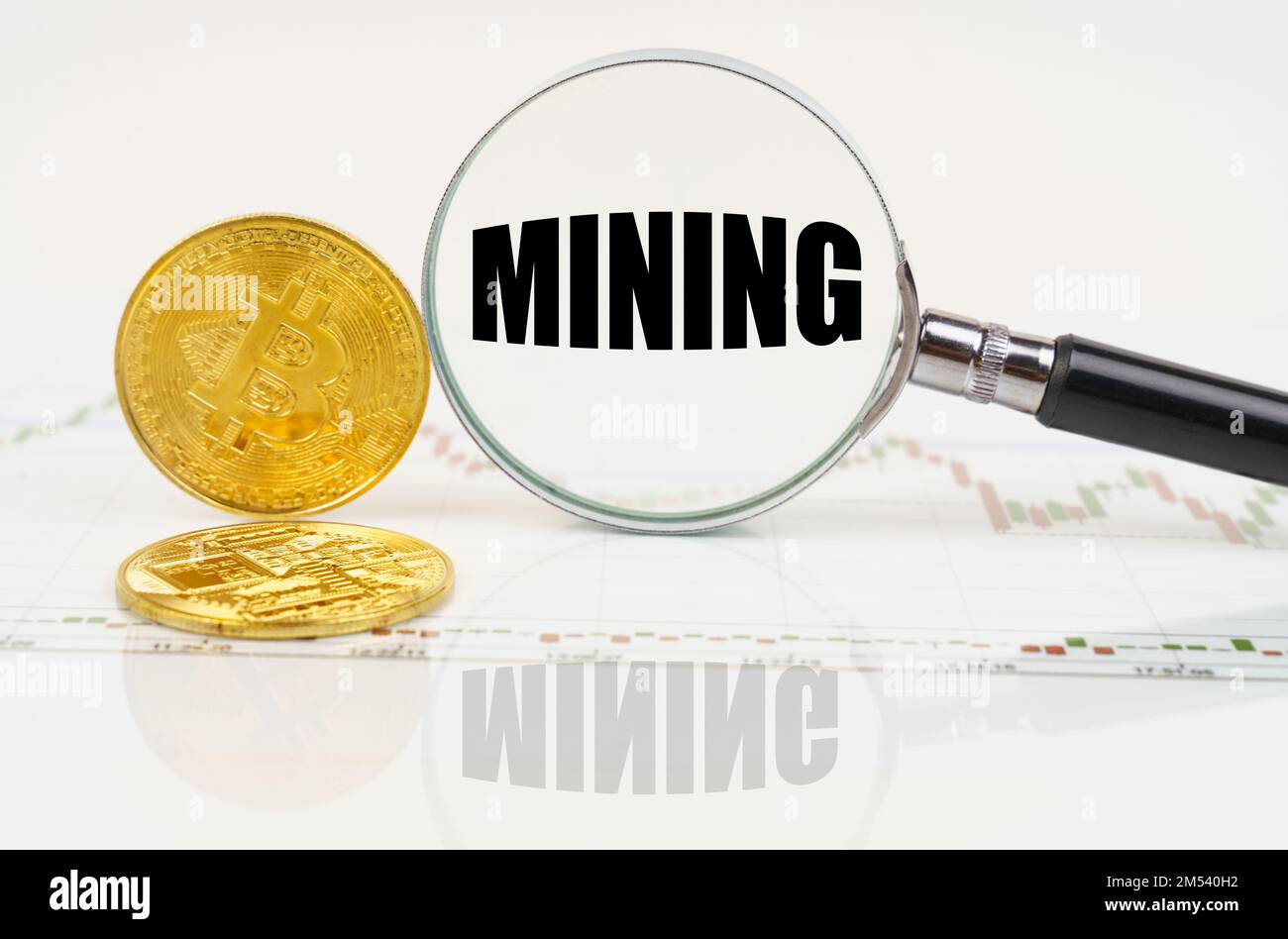 Business and technology concept. There are bitcoins on the chart and there is a magnifying glass with the inscription - Mining Stock Photo