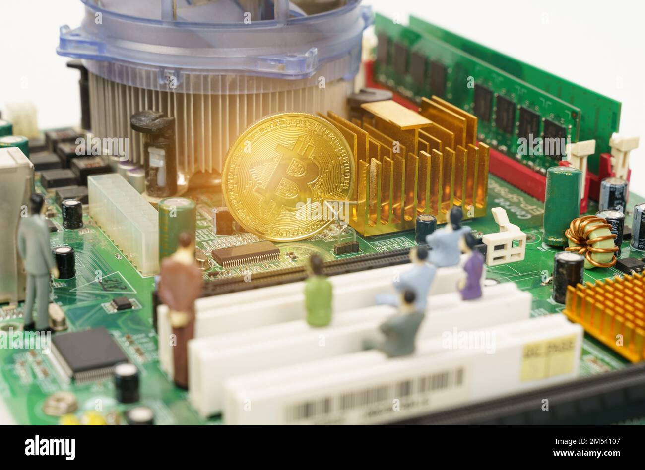 Business and technology concept. On the motherboard of the computer is a gold bitcoin coin and miniature figures of people. Figures out of focus. Stock Photo