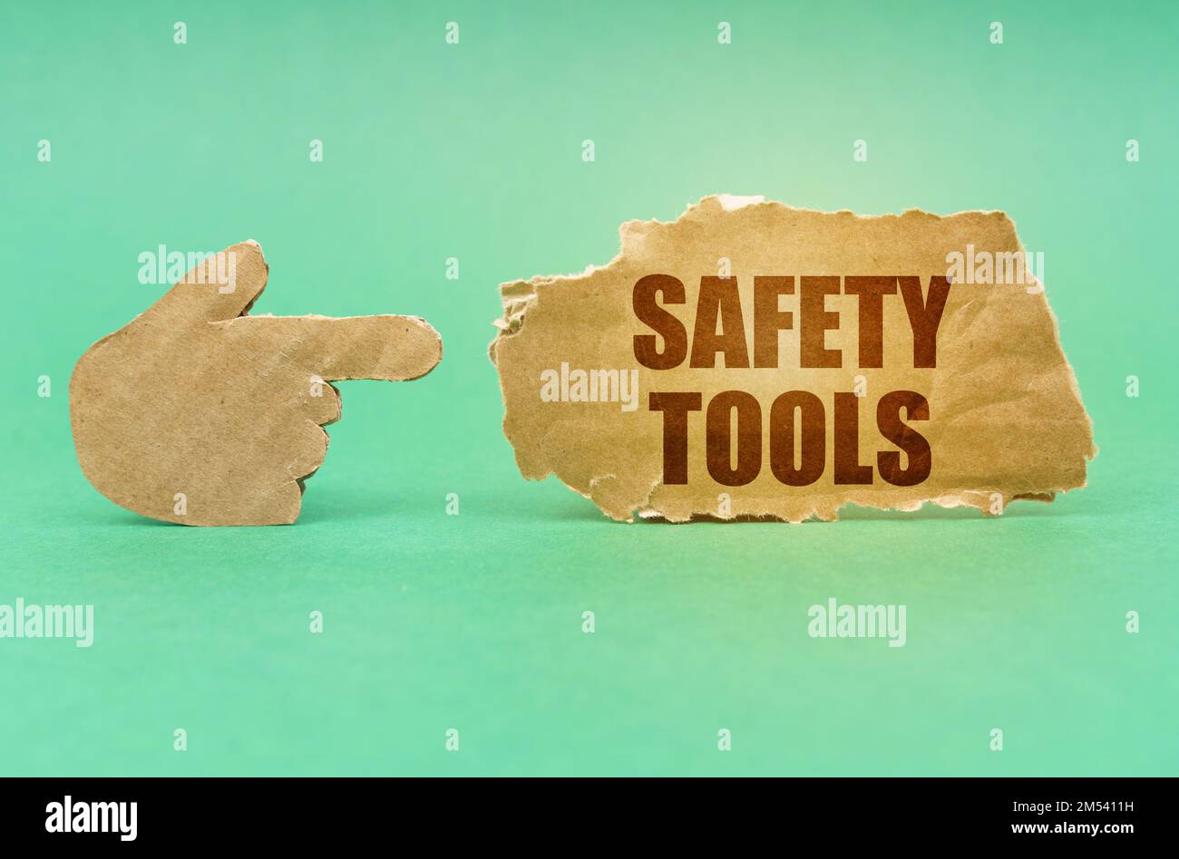 Business concept. On a green surface, a cardboard hand points to a sign with the inscription - Safety Tools Stock Photo