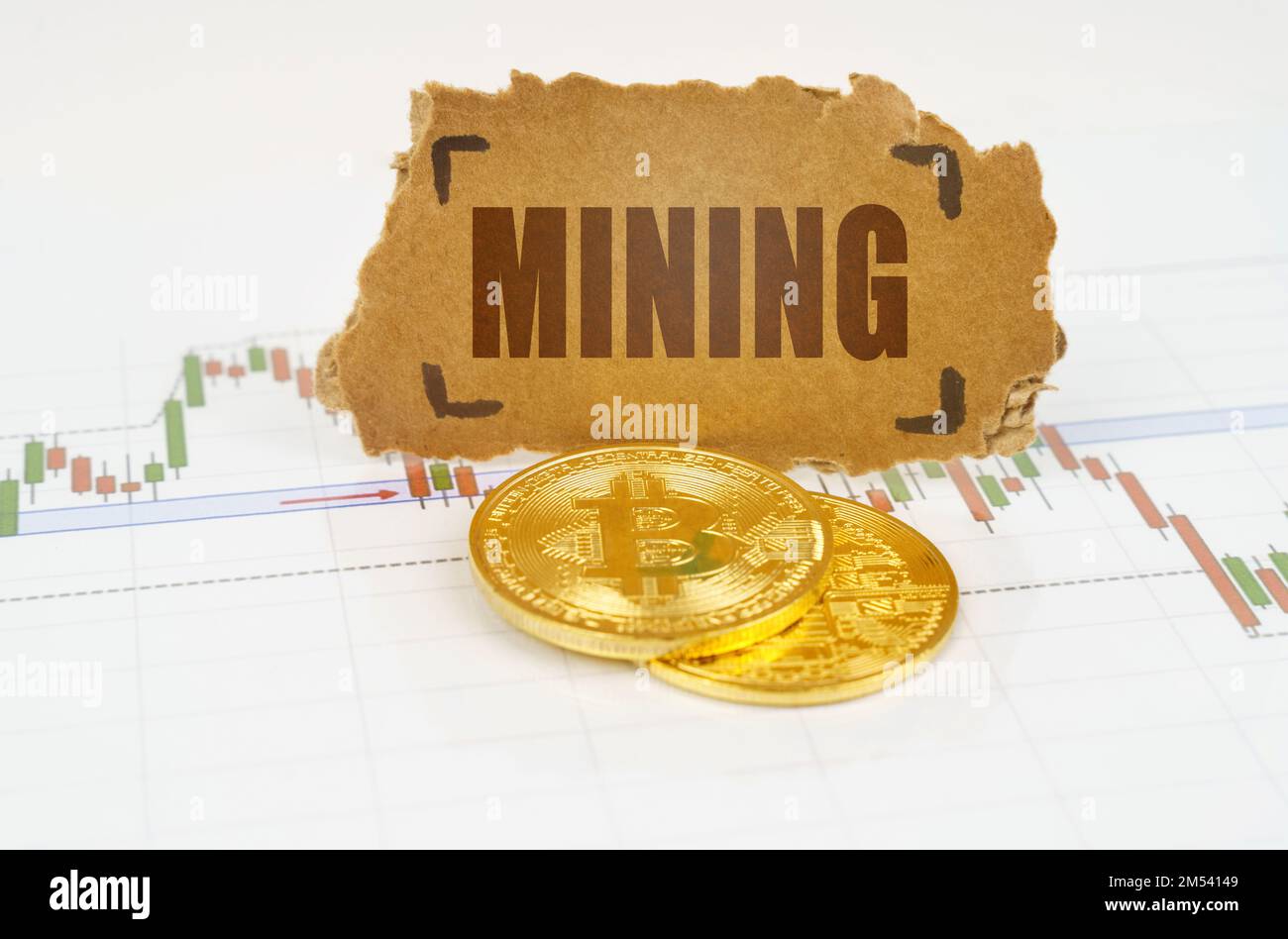 Business and technology concept. On the chart with quotes, there are bitcoins and there is a sign with the inscription - Mining Stock Photo