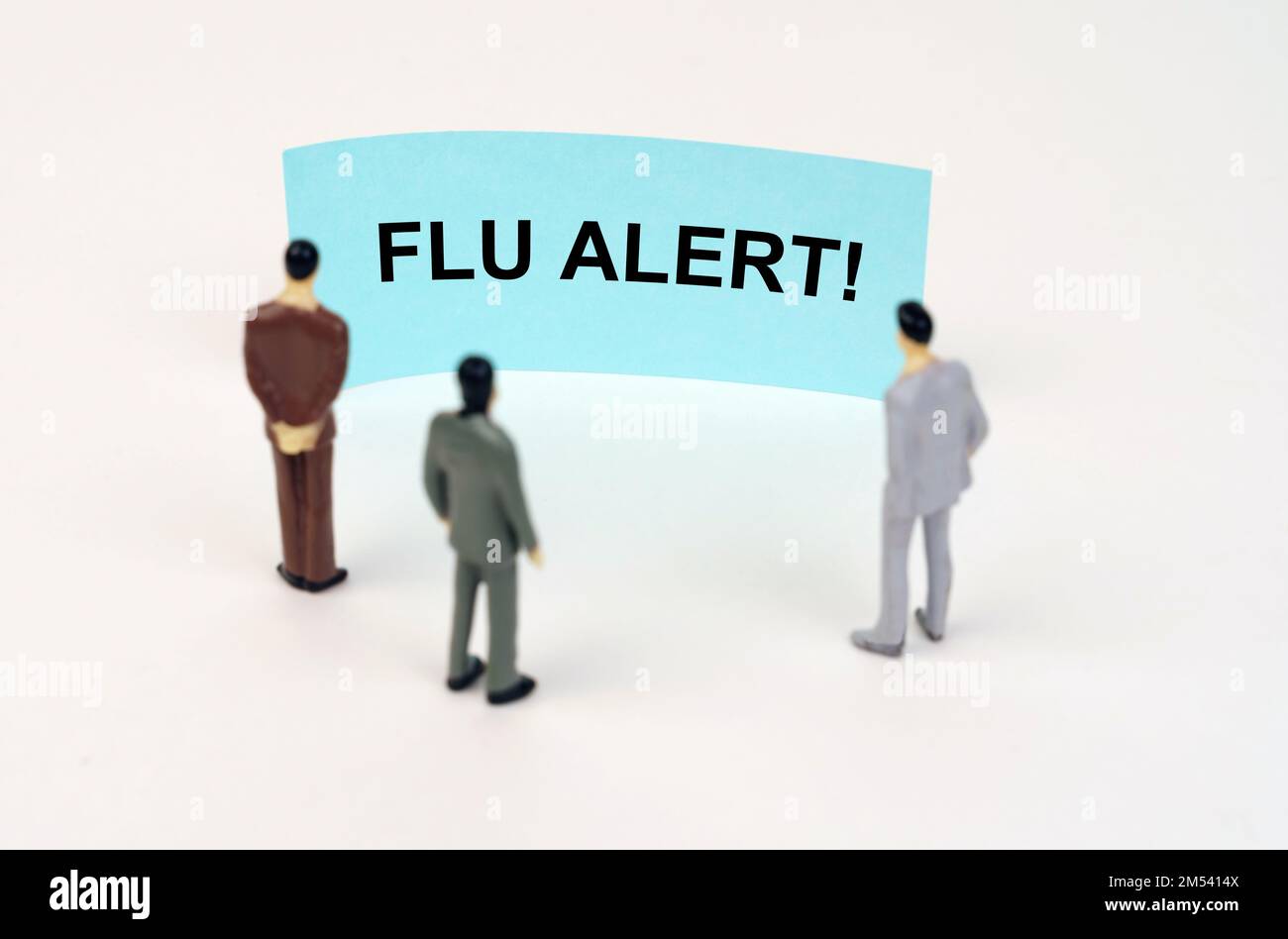 Medical concept. Miniature figures of people stand in front of a blue sign with the inscription - Flu alert Stock Photo