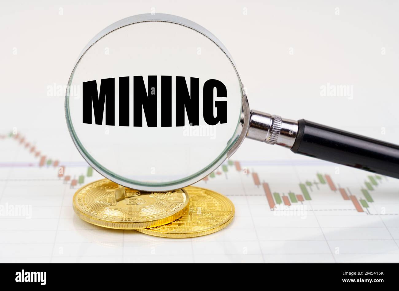 Business and technology concept. On the chart with quotes are bitcoins and there is a magnifying glass with the inscription - Mining Stock Photo