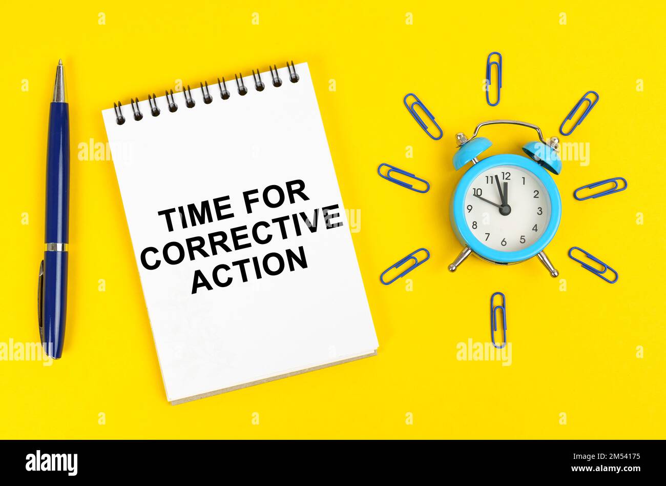 Business and technology concept. On a yellow surface there is an alarm clock, a pen and a notepad with the inscription - Time for Corrective Action Stock Photo