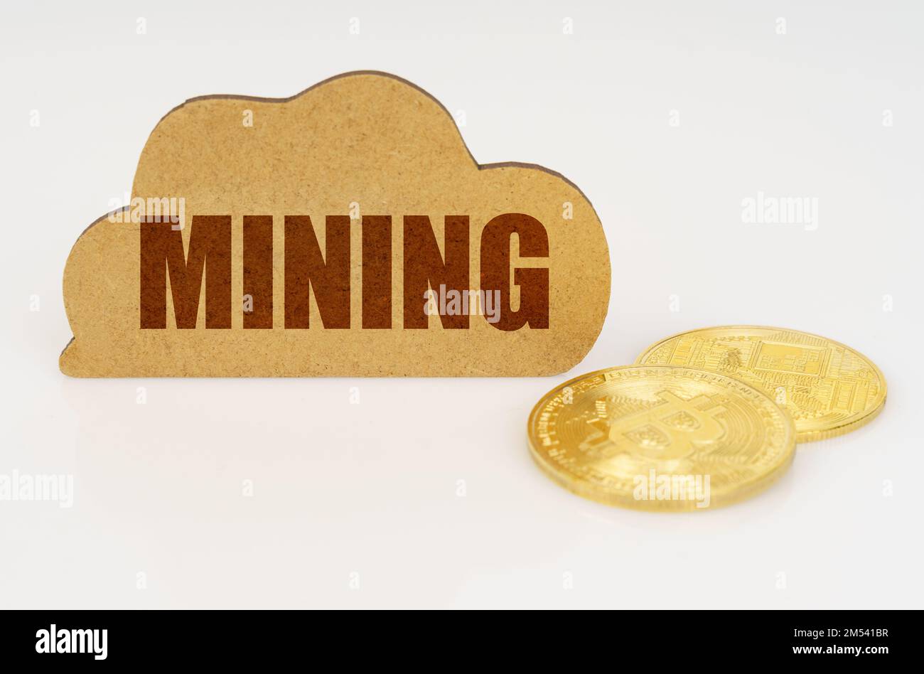 Business and technology concept. Bitcoins lie on a white surface and there is a sign - a cloud with the inscription - Mining Stock Photo
